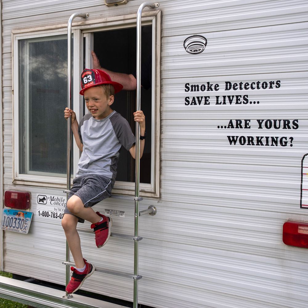child climbing out of a window in a fire safety drill demonstration