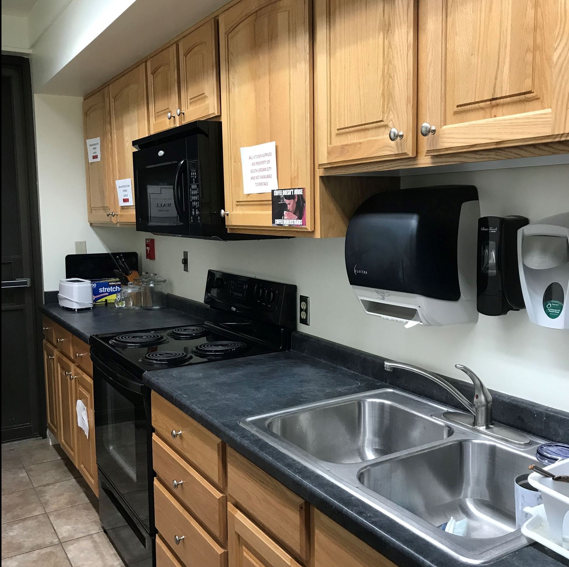 small narrow kitchen with wooden cabinets and dark countertops with black appliances
